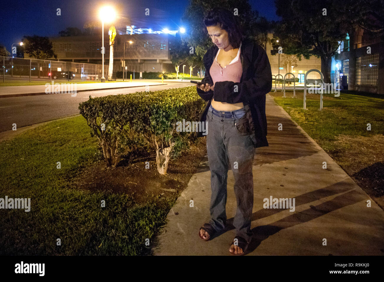 An released county jail inmate uses a donated cell phone to call for a ride at night in Santa Ana, CA. Stock Photo