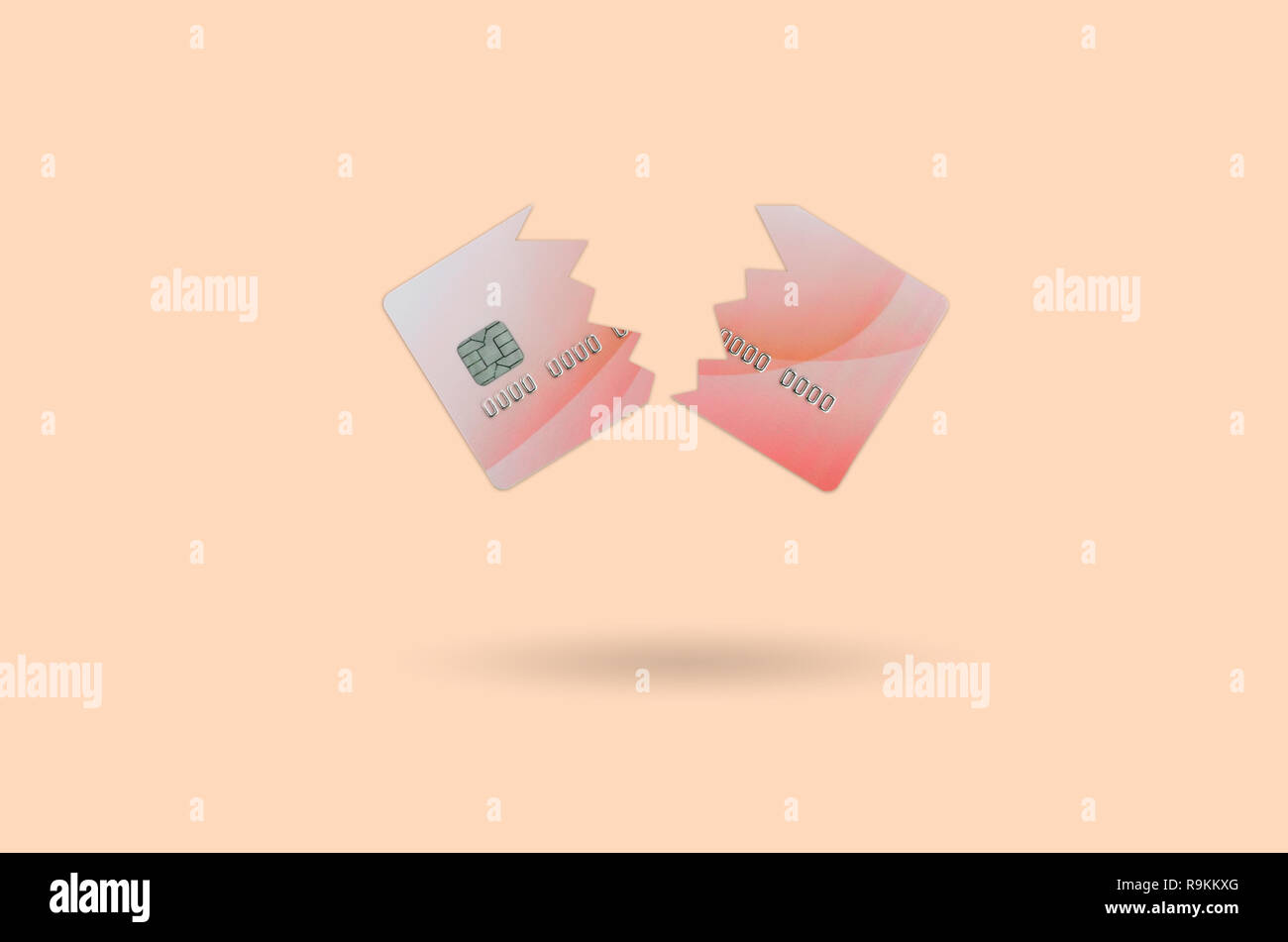 Cut and broken red credit card floating in the pastel orange space. The concept of ban to use banking services. Credit card expire end soon Stock Photo