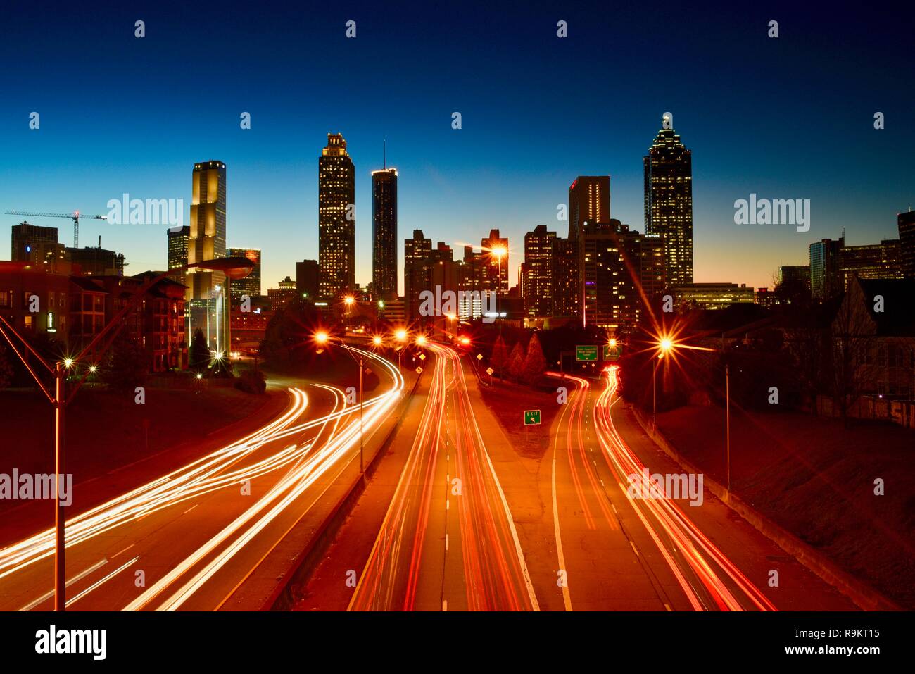 Atlanta downtown skyline lit up at sunset, along busy highway at rush