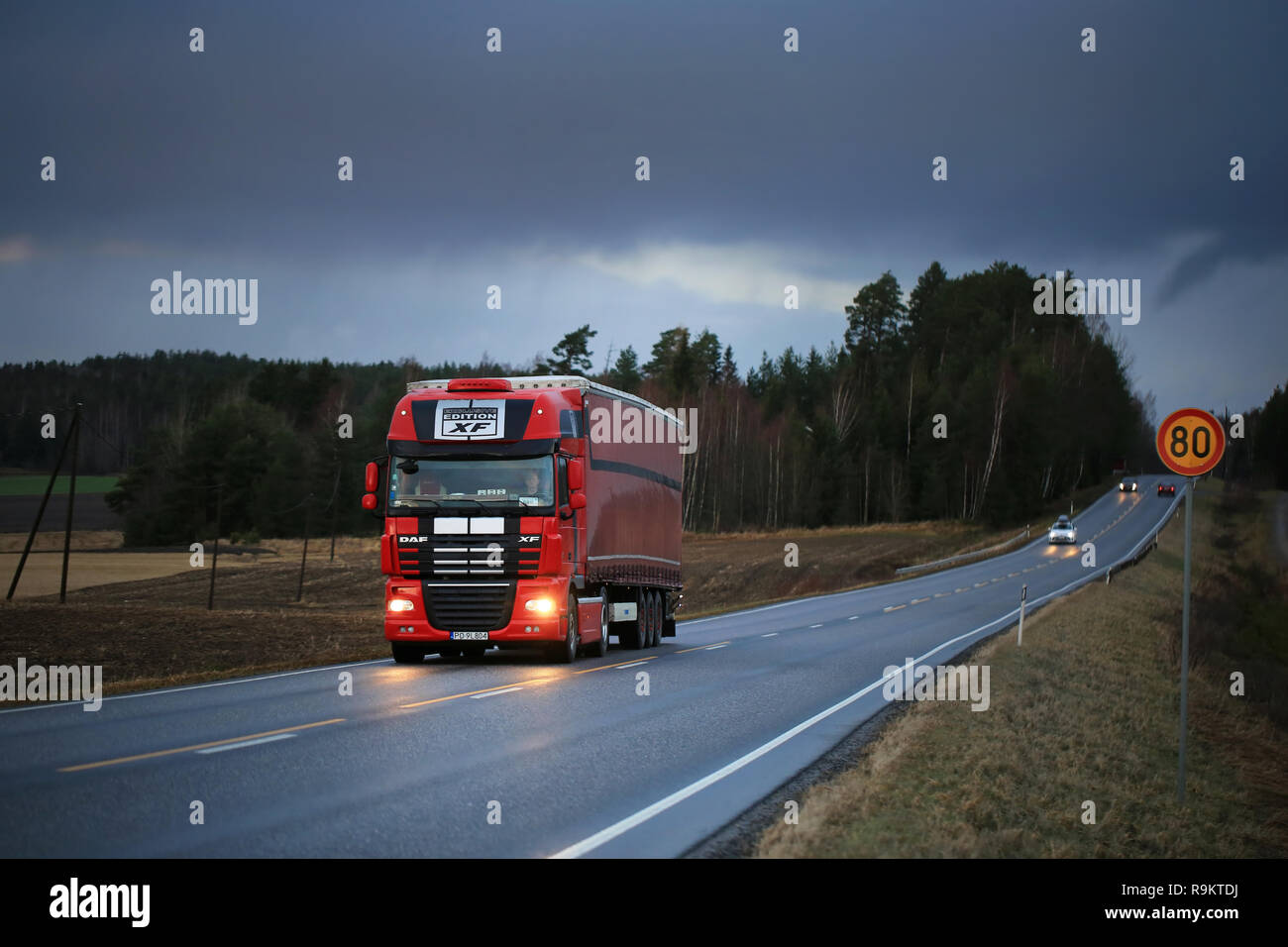 Salo, Finland - December 8, 2017: Red DAF XF Exclusive edition semi trailer hauls goods under dark sky along rural highway in South of Finland. Stock Photo