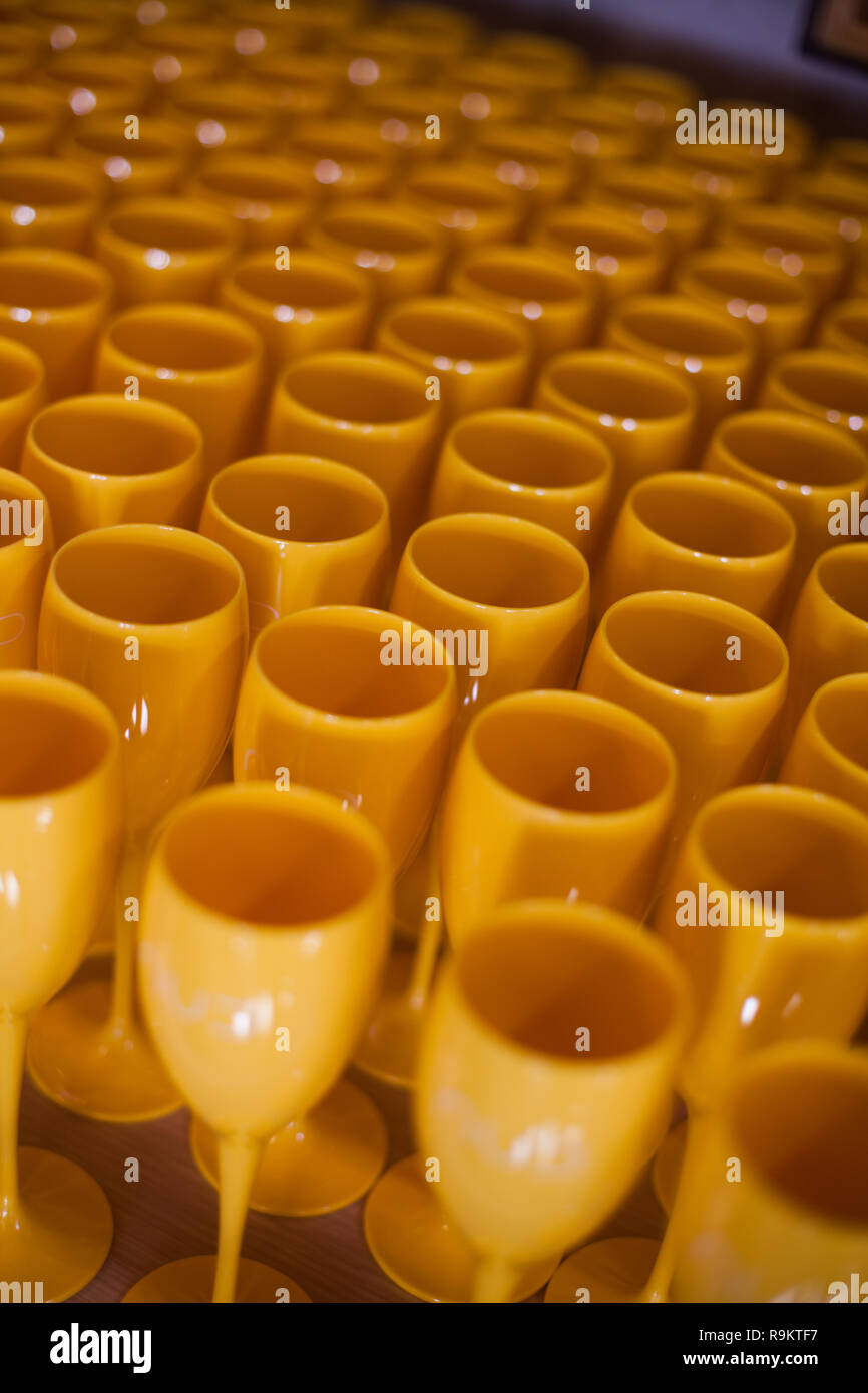Many yellow plastic wine glasses on a table. Stock Photo