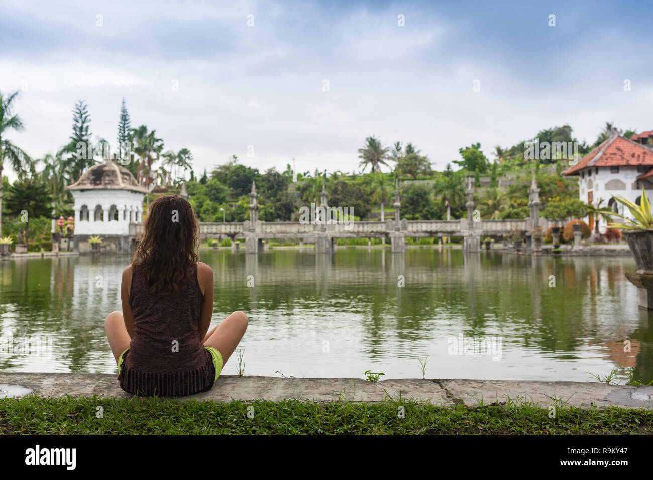 Girl sitting on pier and lookingat the river in Bali Stock Photo - Alamy