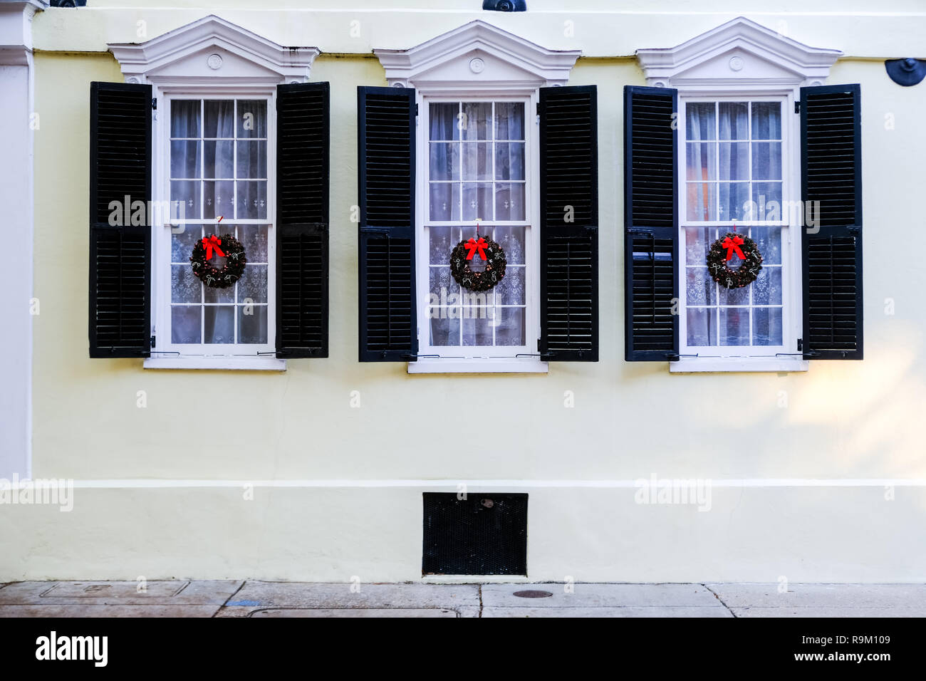 Christmas holiday wreaths decorate windows on a historic home during the holidays along Tradd Street in Charleston, South Carolina. Stock Photo