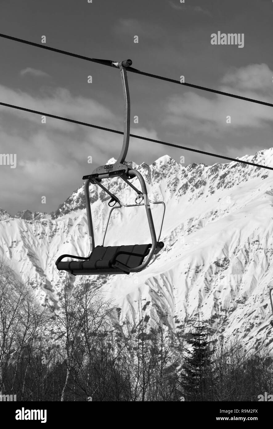 Ski-lift on ski resort and snowy mountains at sunny day. Caucasus Mountains in winter. Hatsvali, Svaneti region of Georgia. Black and white toned land Stock Photo