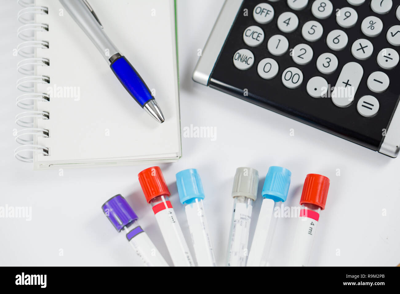 Medicine bottles for samples next to calculator and notebook in hospital or laboratory, closeup on white background Stock Photo