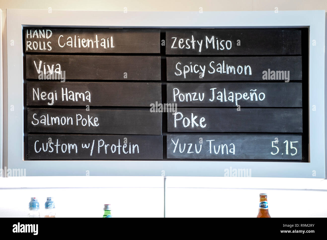 The wall display menu of a Costa Mesa, CA, Japanese fast food restaurant lists a choice of fish ingredients for hand rolls and poke dishes. Stock Photo