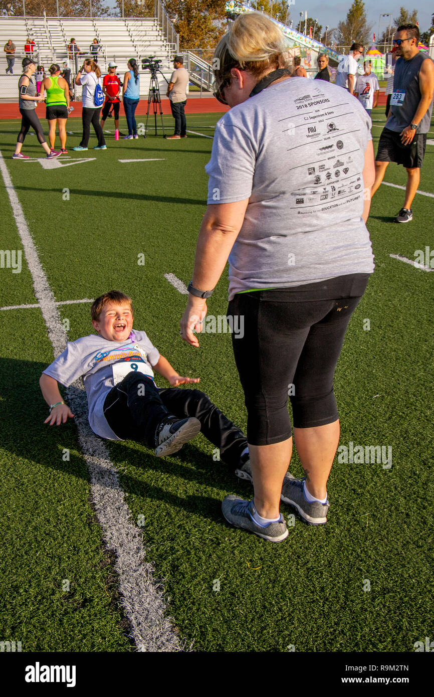 As his mom obligingly holds down his toes, an 8-year-old boy does some preparatory sit ups before running in a community foot race in Costa Mesa, CA. Stock Photo