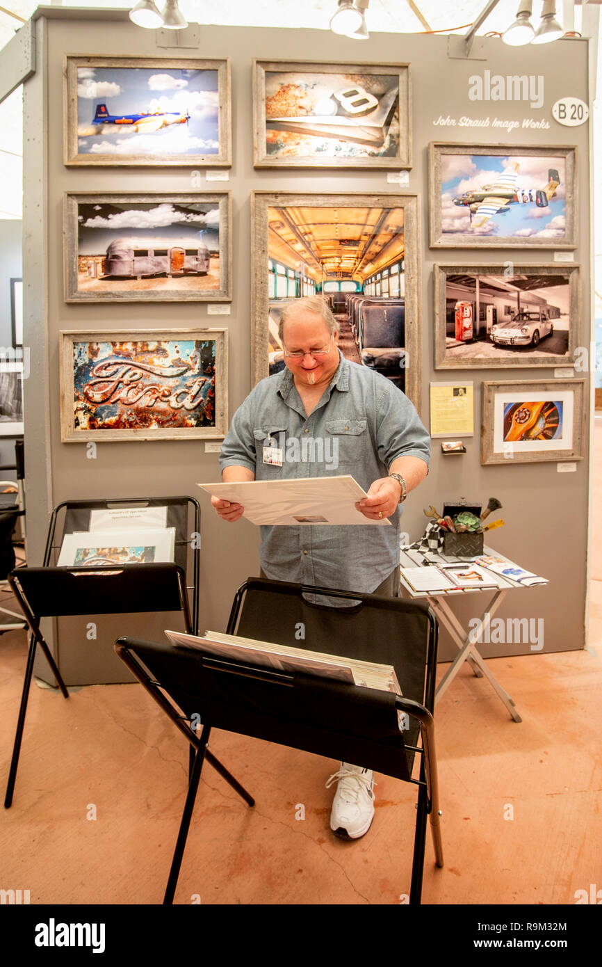 An artist arranges a display of his prints depicting transportation and aviation themes at an art fair in Laguna Beach, CA. Stock Photo