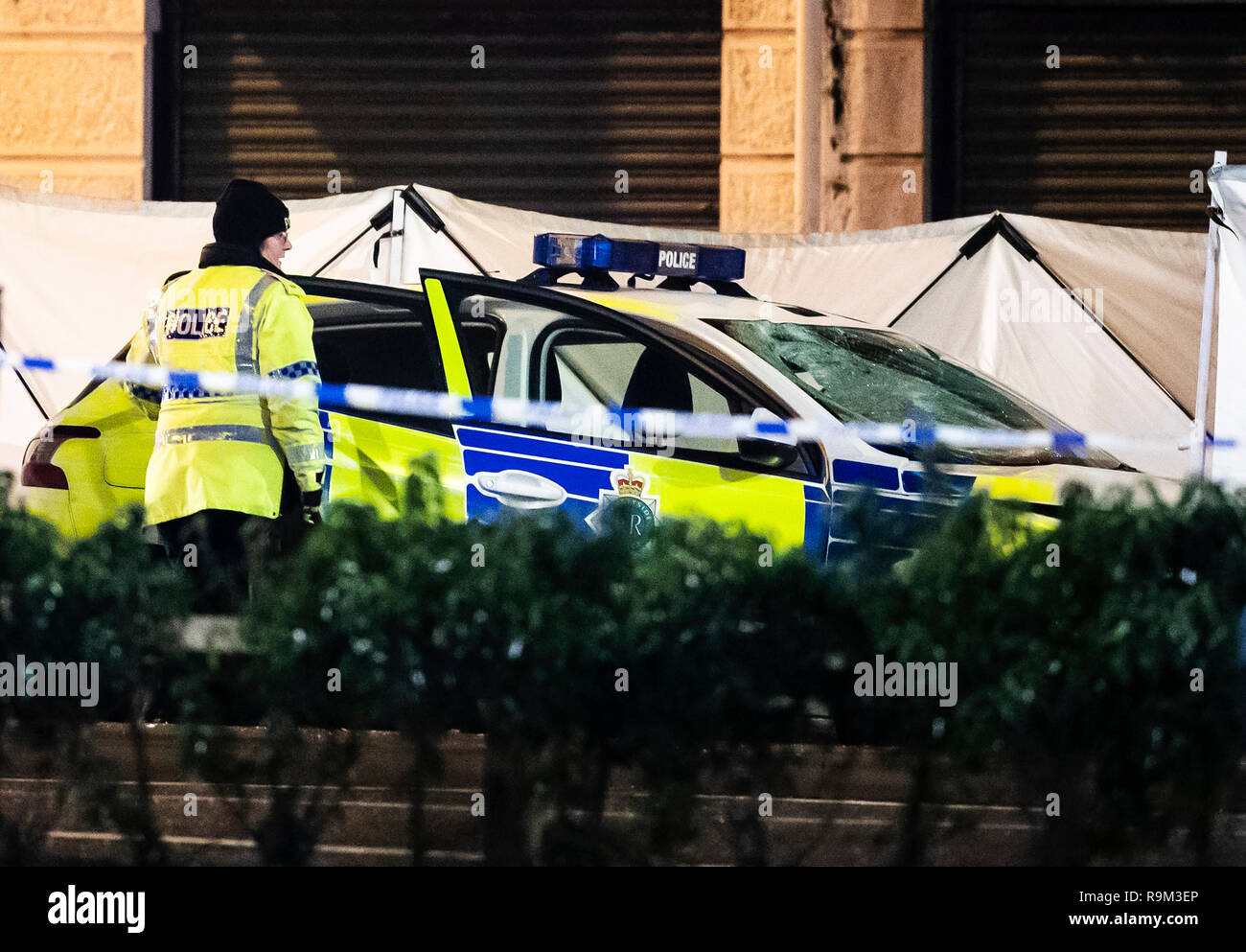 A screen surrounds a police vehicle with a smashed windscreen at the ...