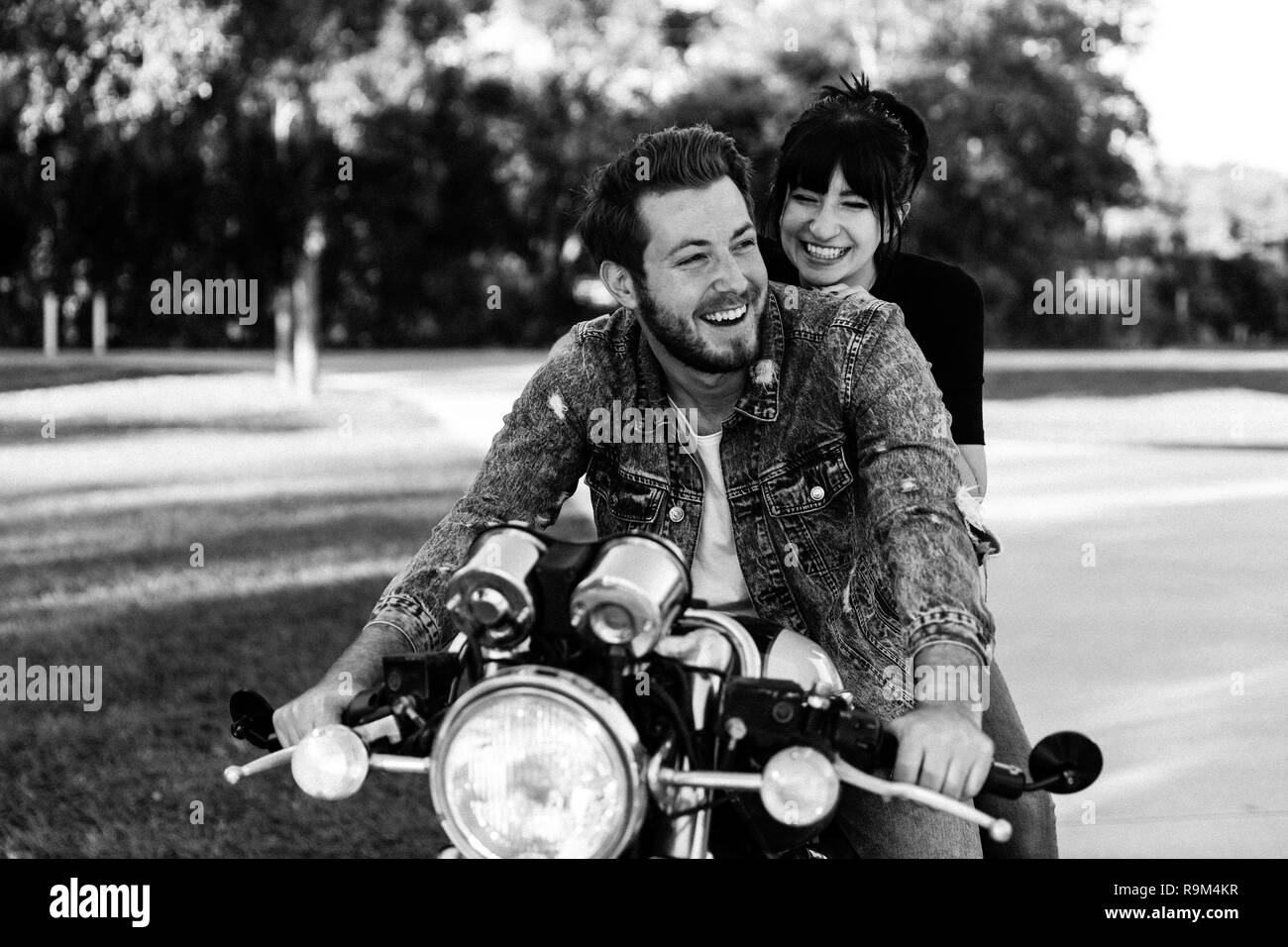Portrait of Attractive Good Looking Young Modern Trendy Fashionable Guy Girl Couple Riding on Green Motorcycle Cruiser Classic Bike in Love Stock Photo