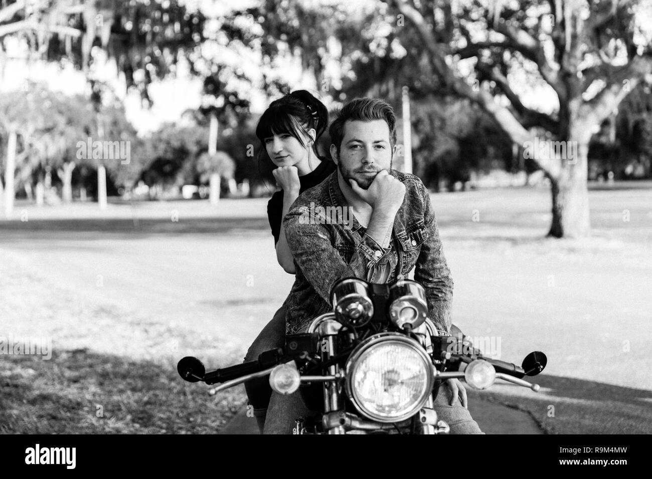 Portrait of Attractive Good Looking Young Modern Trendy Fashionable Guy Girl Couple Riding on Green Motorcycle Cruiser Classic Bike in Love Stock Photo