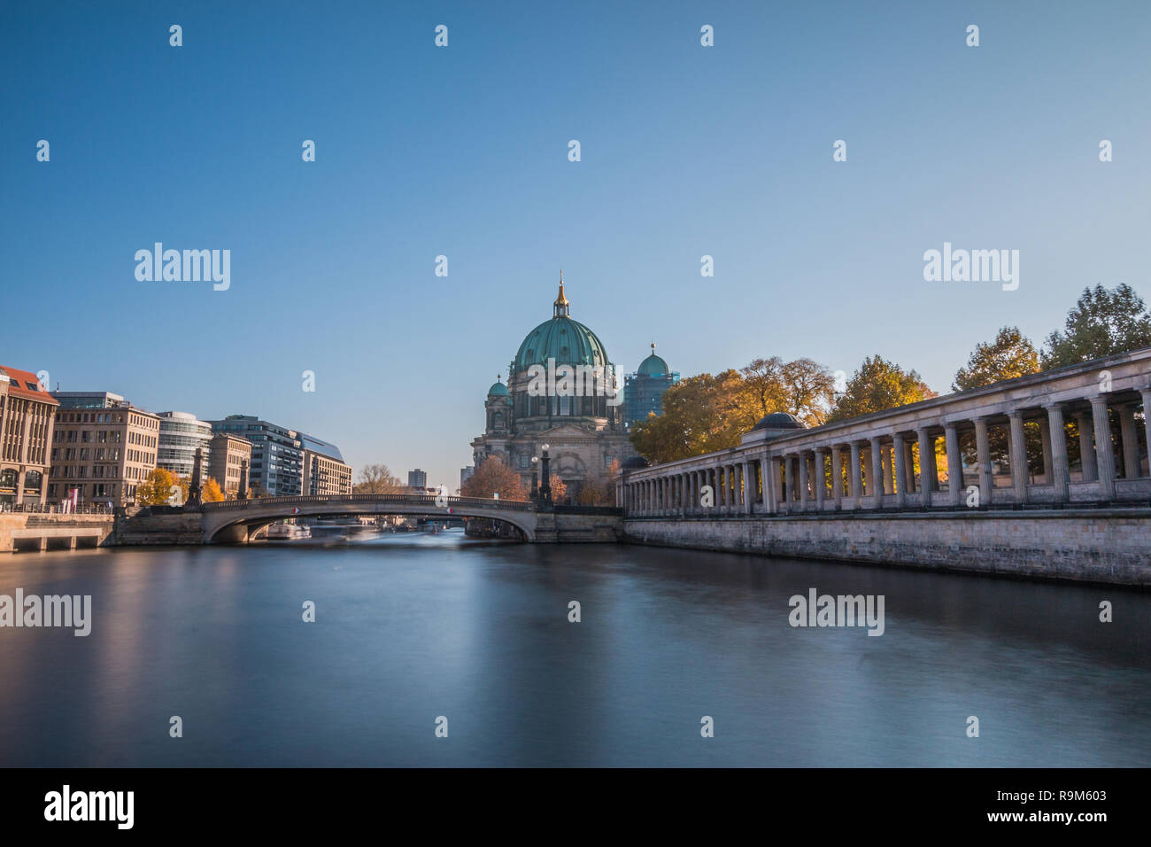 Berlin Cathedral with the Friedrich's Bridge at blue sky. Arcade of the National Gallery on the river bank of the river Spree with buildings. Stock Photo