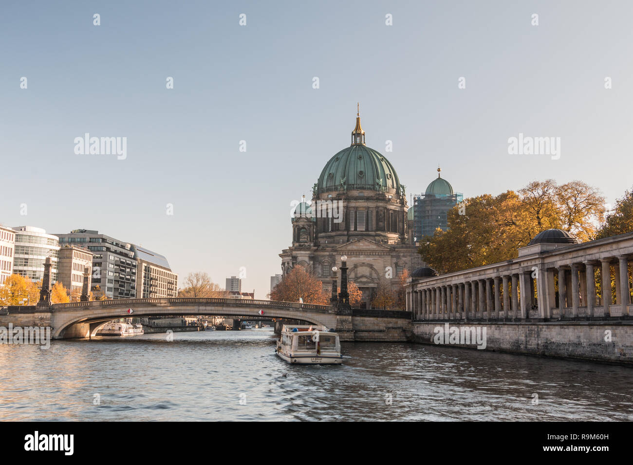 Berlin Cathedral with the Friedrich's Bridge at blue sky. Colonnade of the National Gallery on the river bank of the Spree with boat on the canal Stock Photo