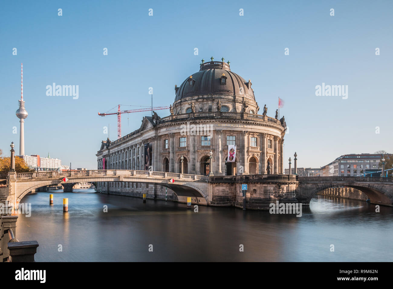 Bode Museum with the river Spree at blue sky. Historic bridges across the river to Museum Island with smooth water surface. TV tower in the background Stock Photo