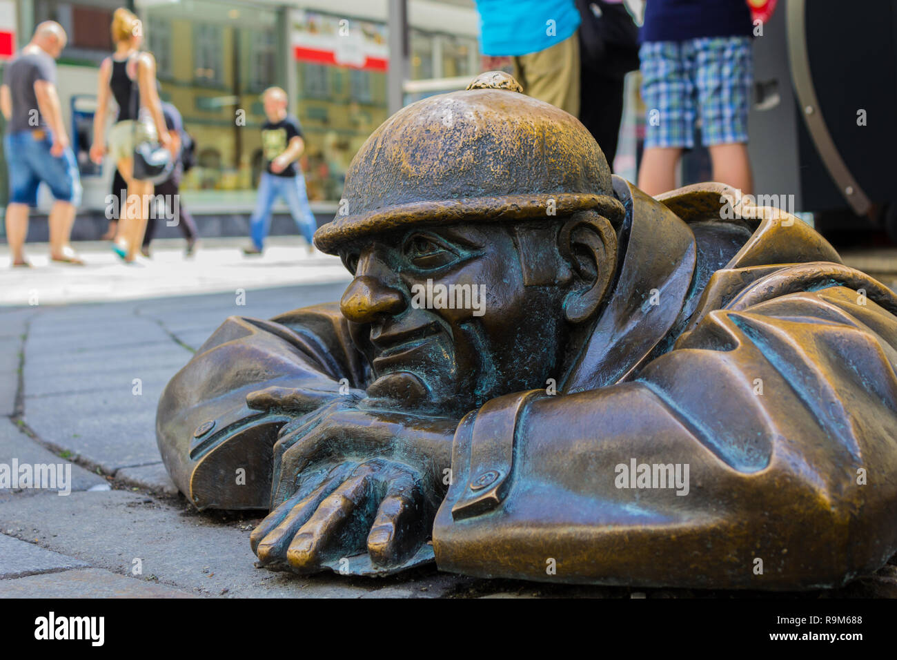 Statue of a man peaking out from under a manhole cover in Bratislava, Slovakia on August 2018 Stock Photo