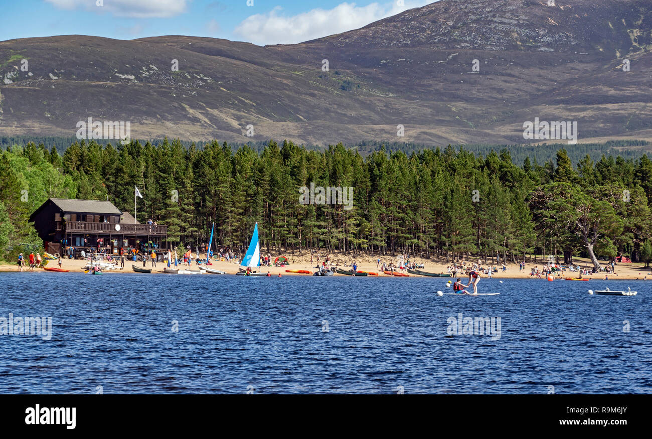 Loch Morlich and Cairngorms in Glenmore Cairngorms National Park Highland Scotland with the east beach full of visitors and boats Stock Photo