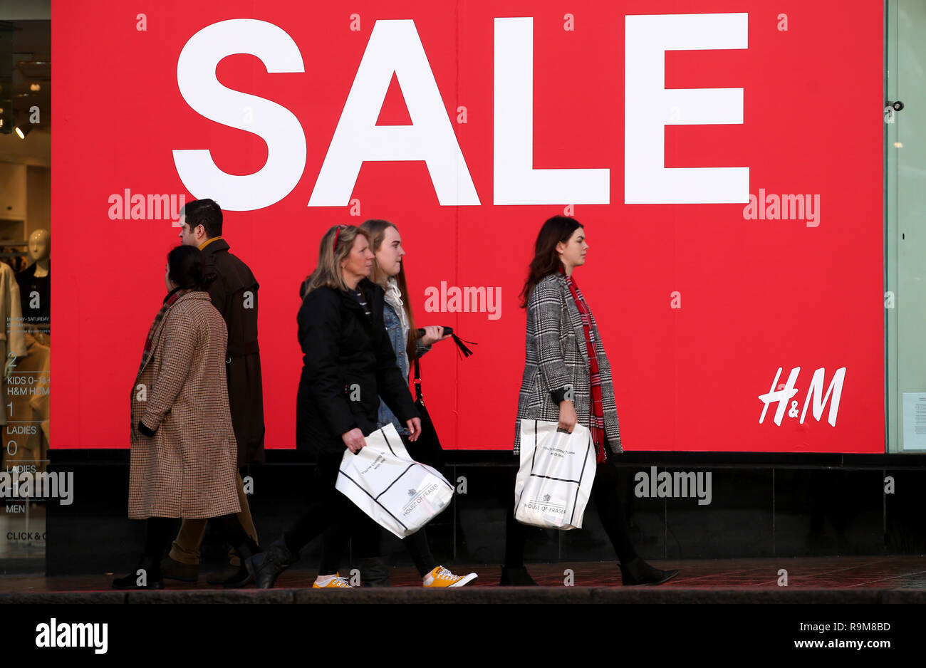 Shoppers pass a sale sign in the window of H&M on Princes Street,  Edinburgh, during the boxing Day sales Stock Photo - Alamy