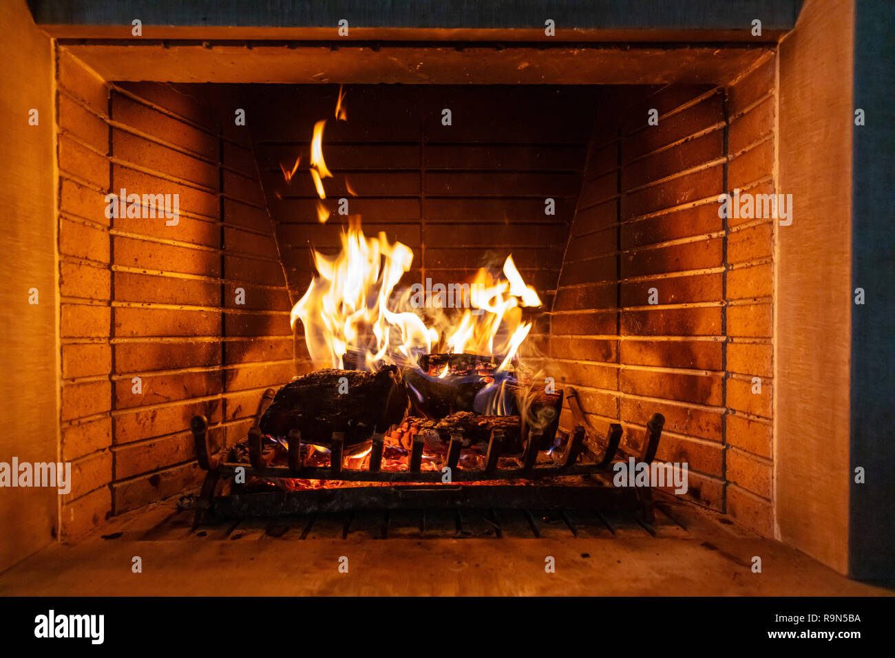 Christmas time, cozy fireplace. Wood logs burning, fire bricks