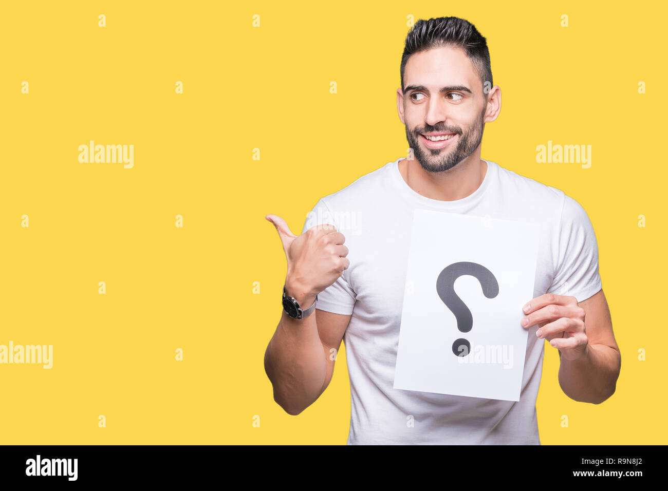 Handsome young man holding paper with question mark over isolated ...