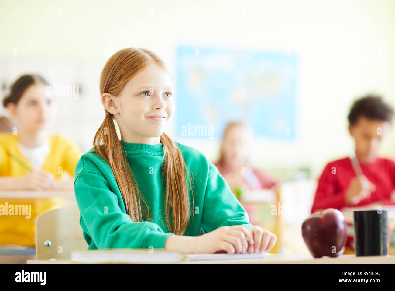 Content redhead girl sitting at desk in school Stock Photo - Alamy