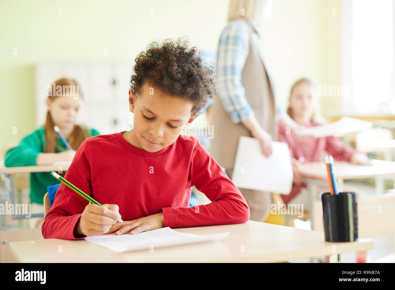 Confident schoolboy marking answers in blank Stock Photo