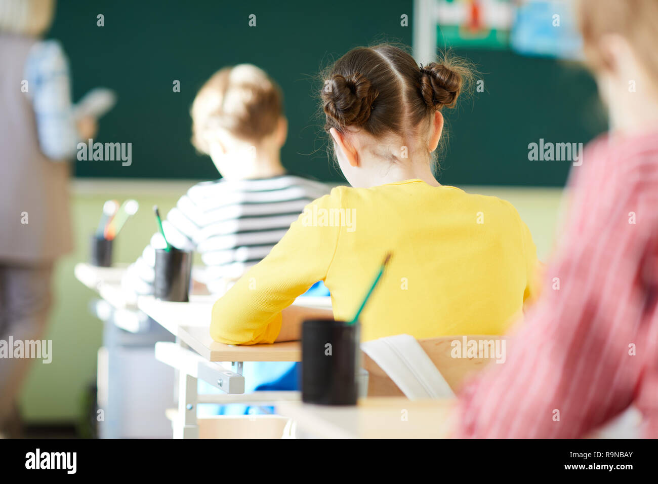 School students writing in workbooks at lesson Stock Photo