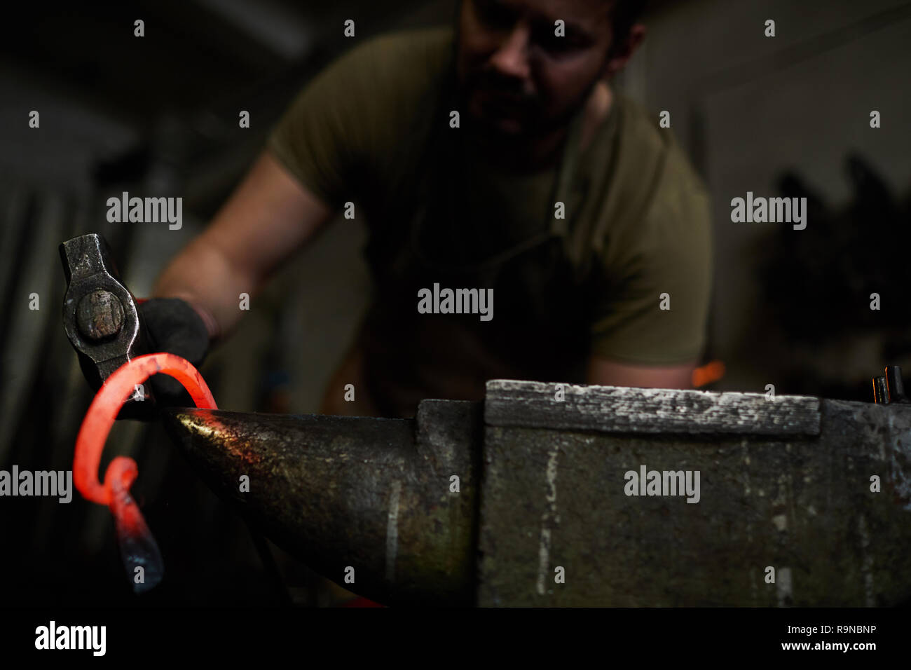 Forging metal in dark workshop Stock Photo