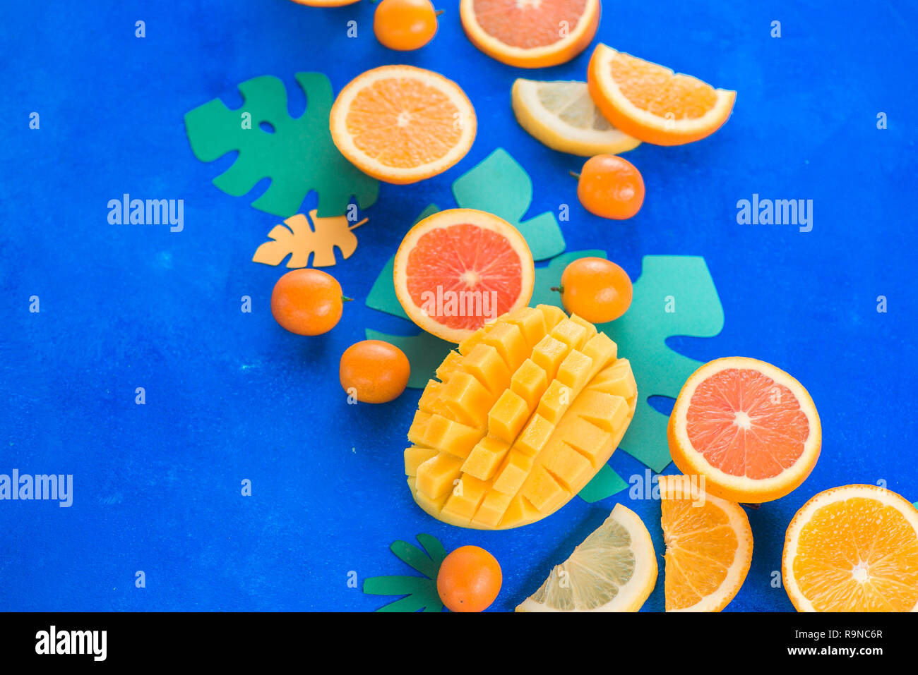 Exotic fruits close-up. Mango, oranges, kumquat and other tropical fruits vibrant blue background with copy space. Stock Photo