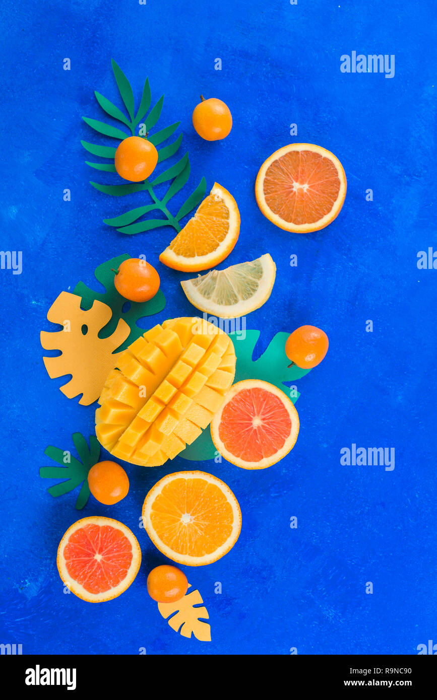 Citrus fruits, mango, oranges, kumquat, and other tropical fruits vibrant blue background with copy space. Exotic fruits close-up. Stock Photo