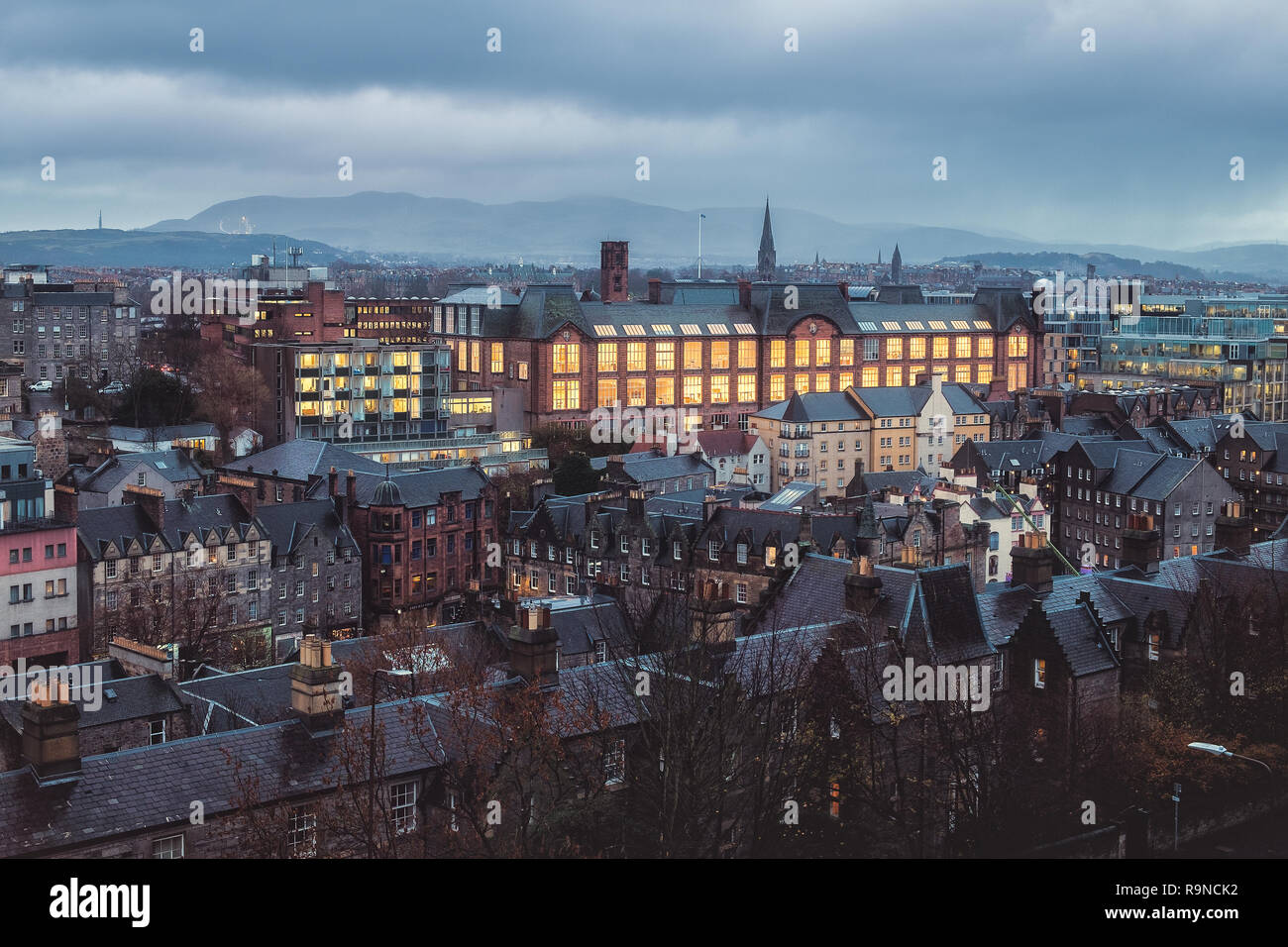 Top view of the night city of Edinburgh, rooftops with chimneys, burning windows and a building Edinburgh College of Art. December 2018. United Kigdom Stock Photo