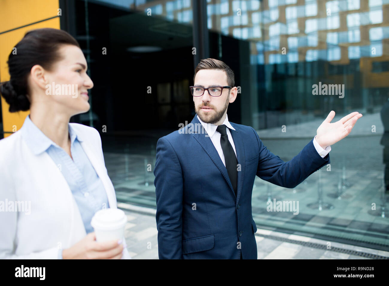Man in formal suit walking with woman and talking Stock Photo