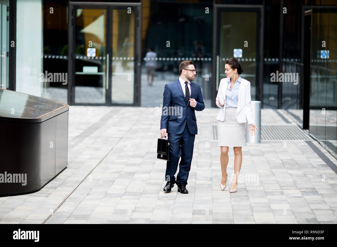 Formal man and woman getting out office building Stock Photo