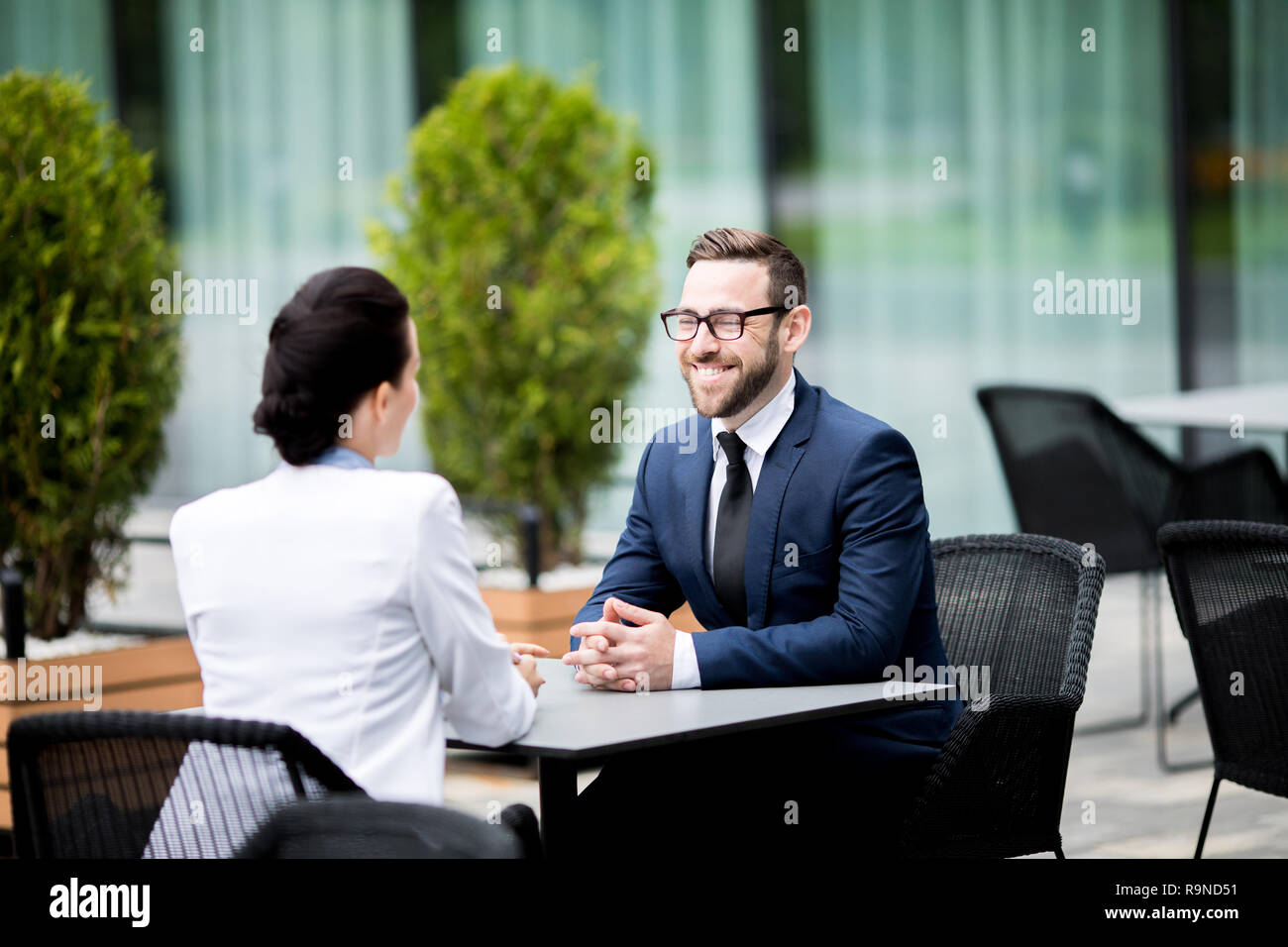 Smiling man and woman sitting at cafe and having dialogue Stock Photo
