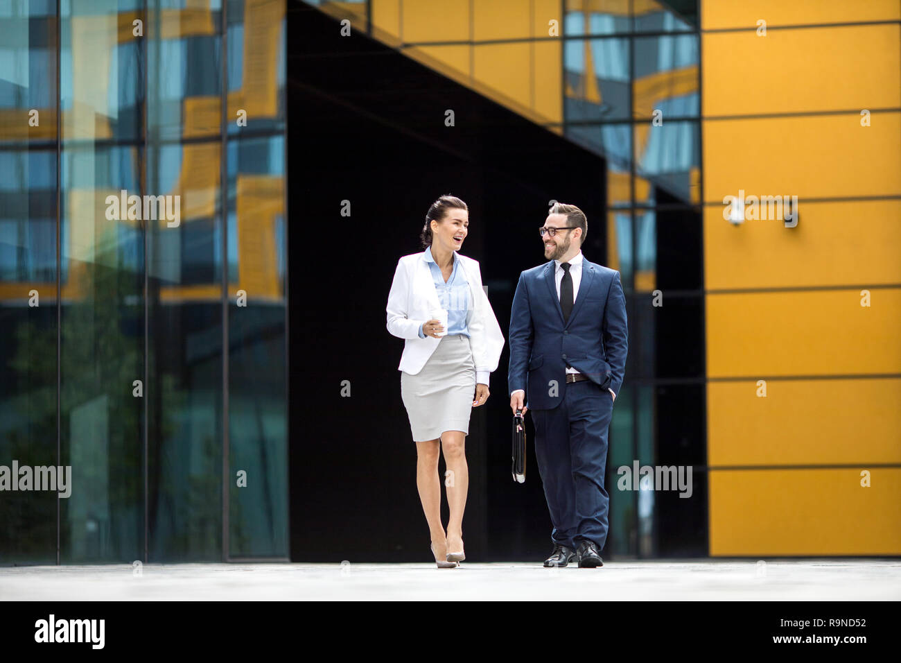 Smiling man and woman getting out office building Stock Photo