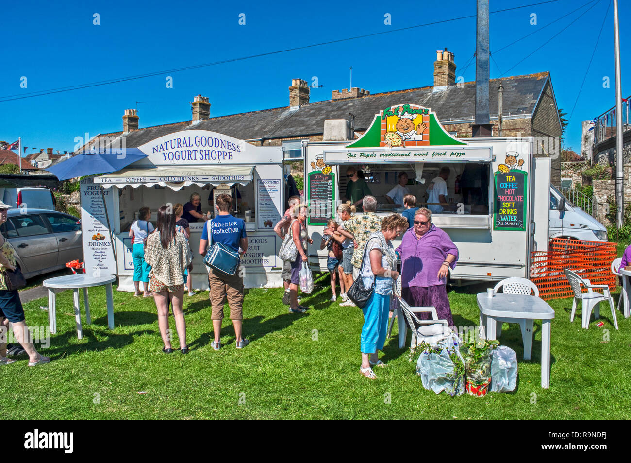 Food kiosks with people serving and customers outside at outdoor event, Isle of Wight, UK Stock Photo