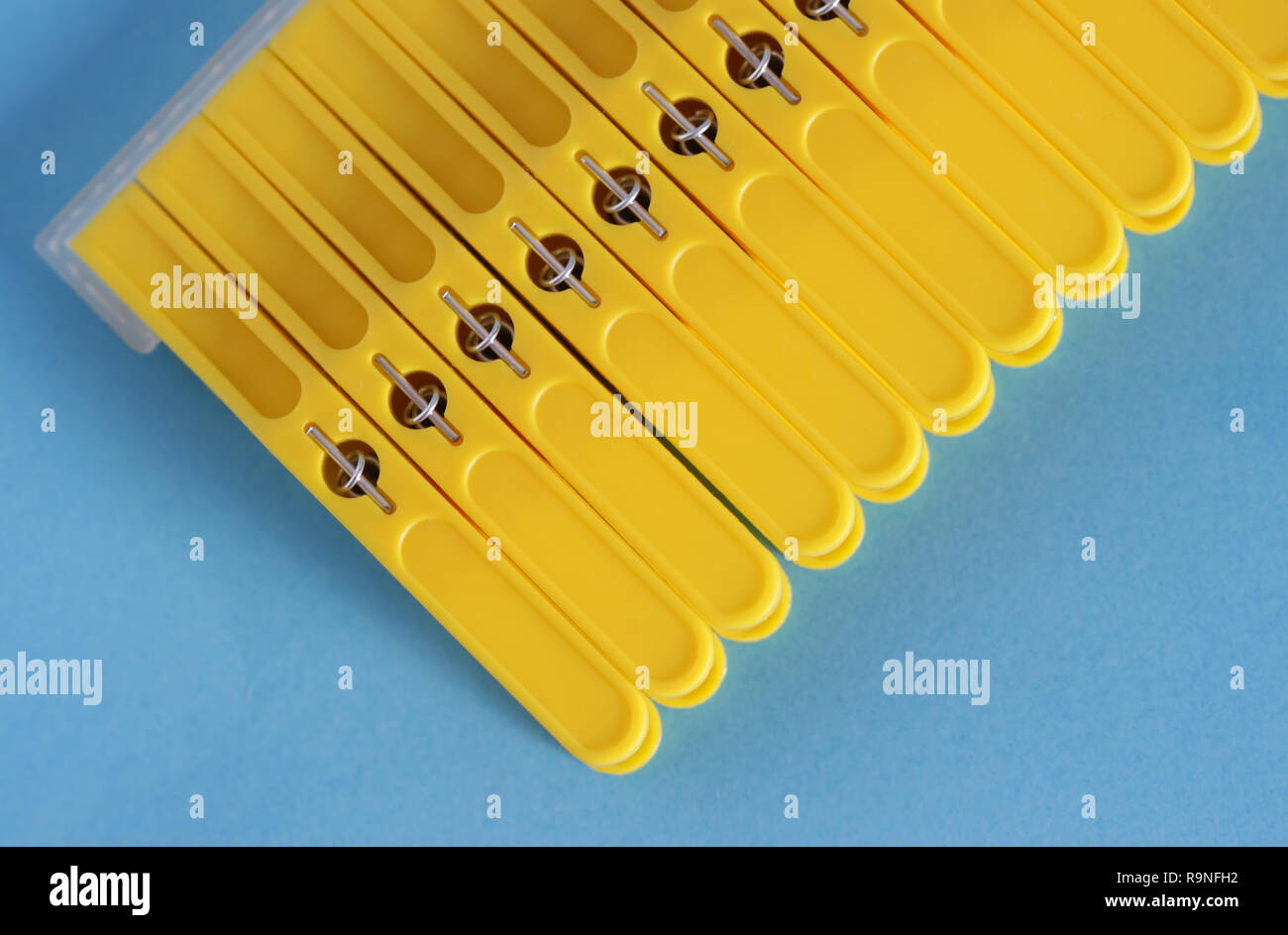 Yellow clothes pins isolated on blue background Stock Photo