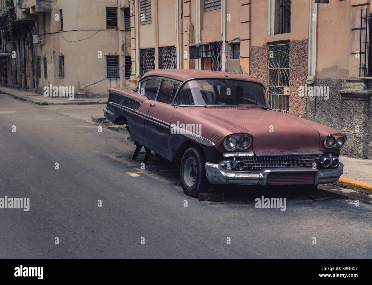 Old rusty car jacked up in the streets of Havana Cuba. It´s an american old timer with the back