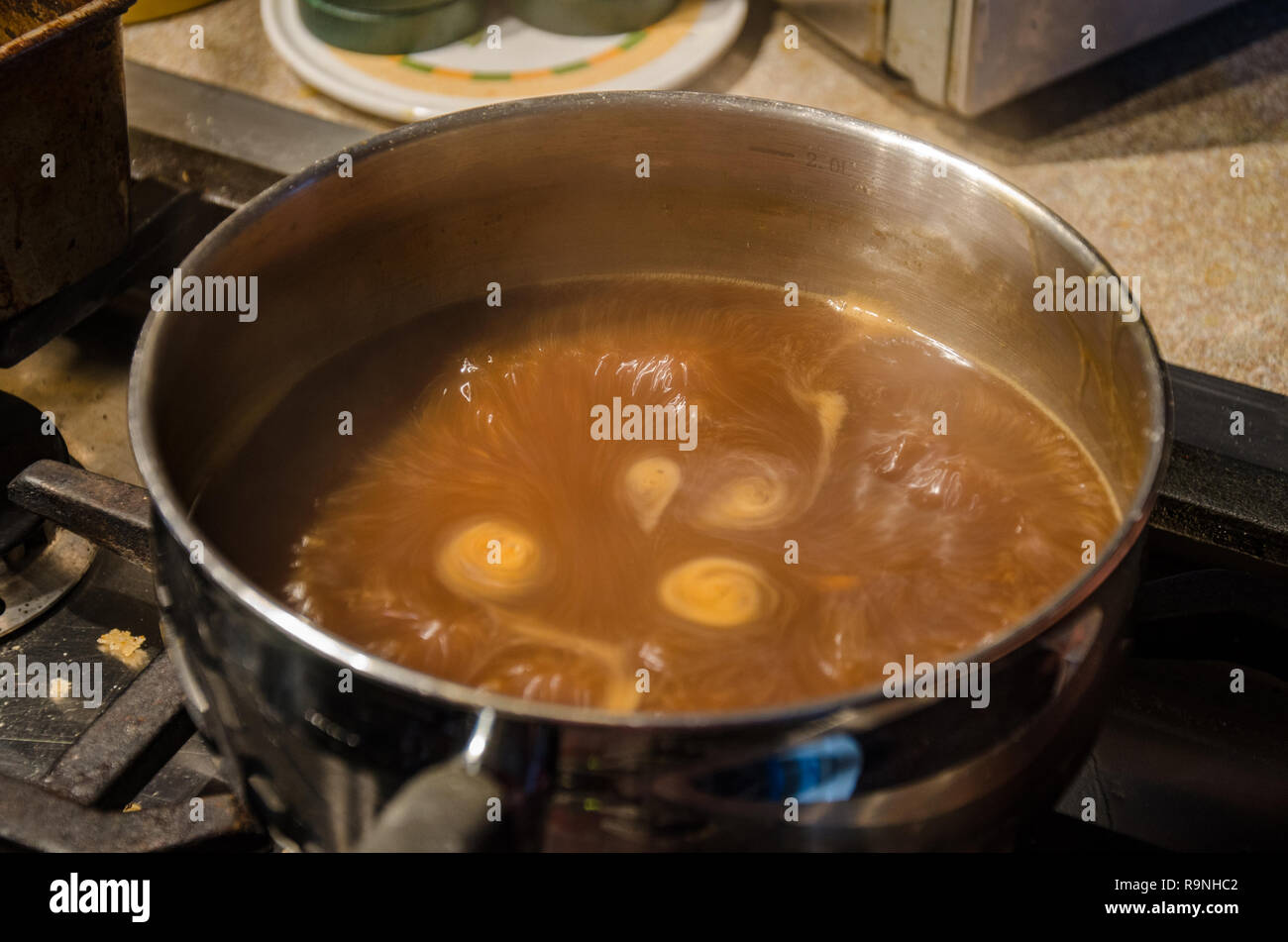Gravy simmering in a saucepan on a hob. Stock Photo