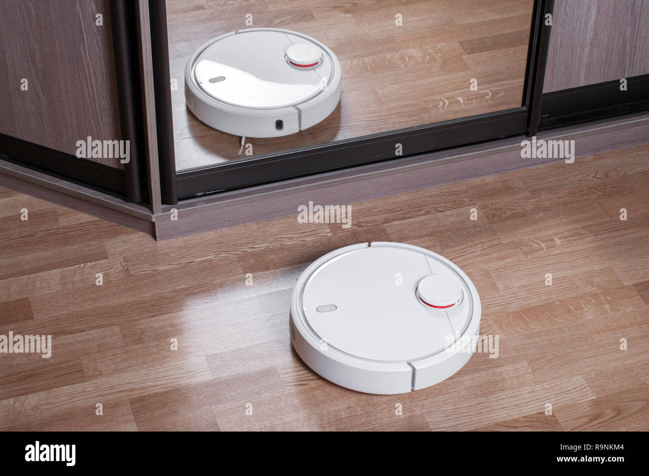 Robot Vacuum Cleaner On Laminate Floor Is Reflected In Mirror Of