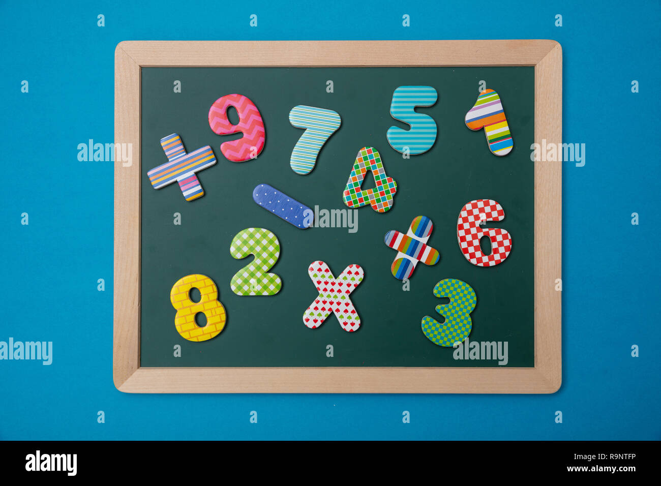 Math, school concept. Green chalkboard with wooden frame, colorful operation signs and numbers, blue background Stock Photo