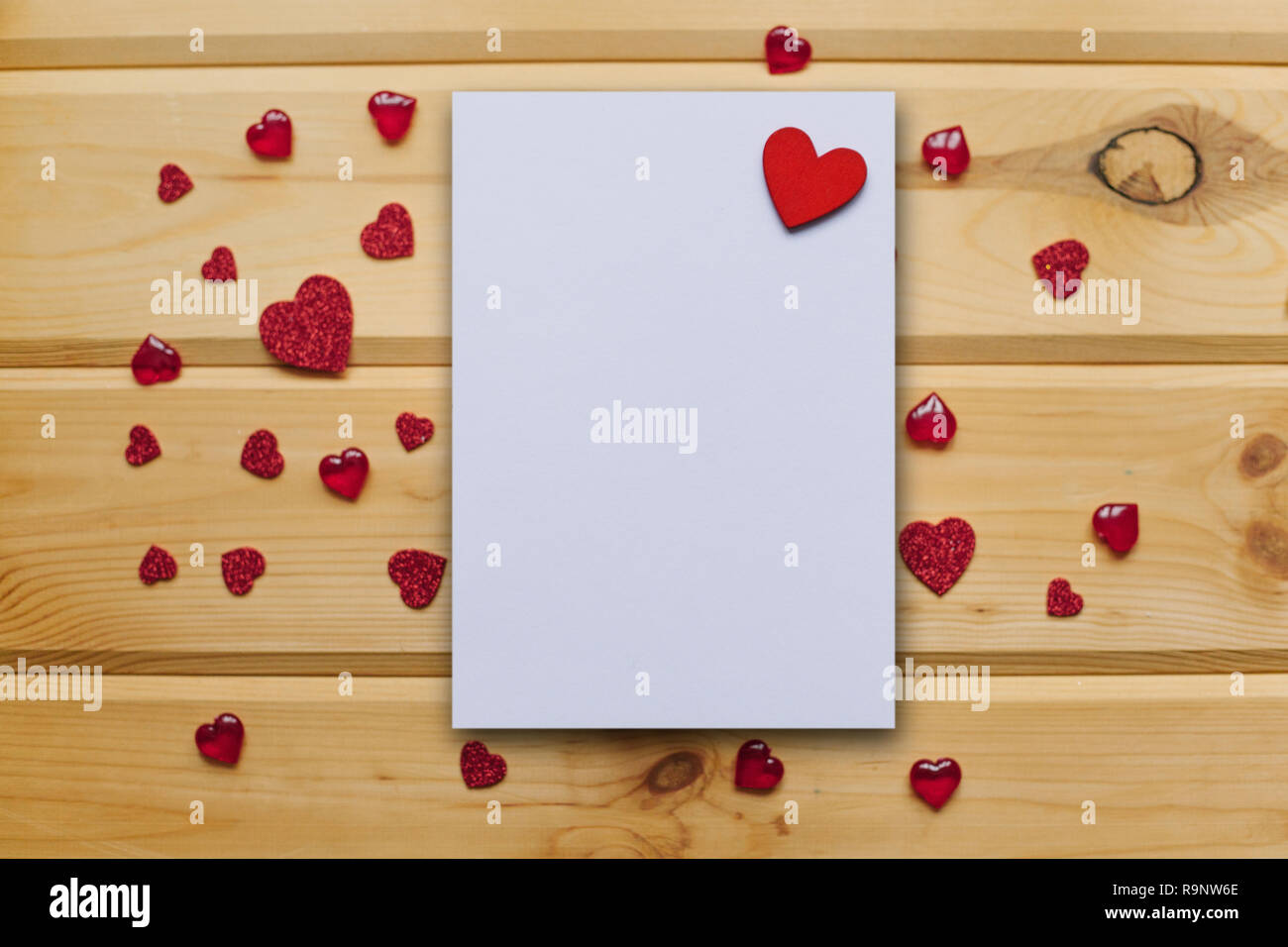 Blank sheet with red heart for text or write on a wooden surface