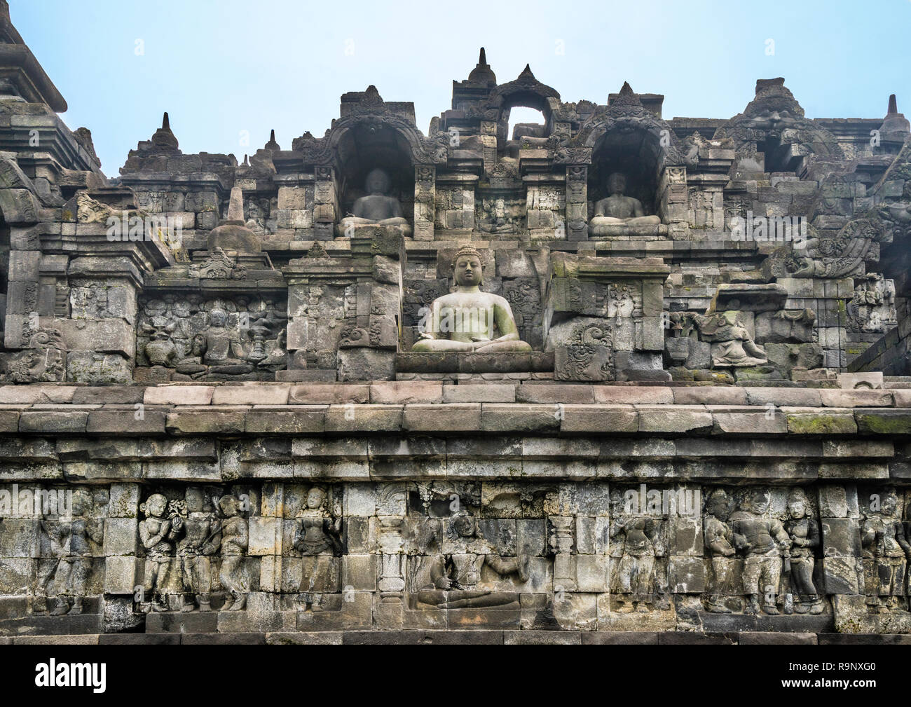 bas-relief panels with narratives of Buddhist mythology and life in Java of the period below niches with sitting Buddha statues on the terraces of 9th Stock Photo