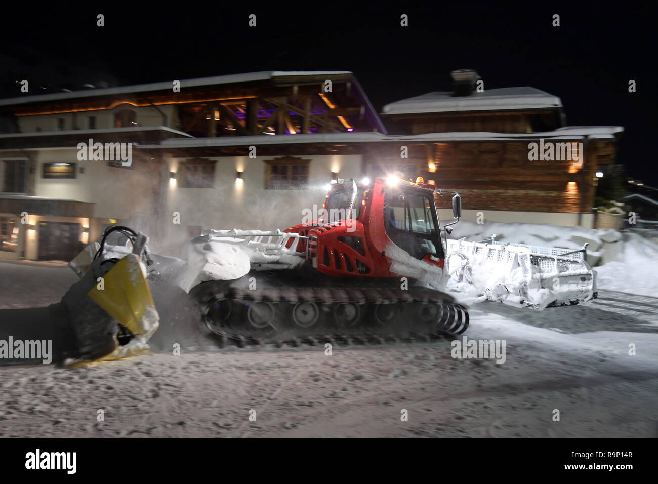 Ratrack snow grooming machine preparing slopes for skiers on ski resort in mountains on night. Stock Photo