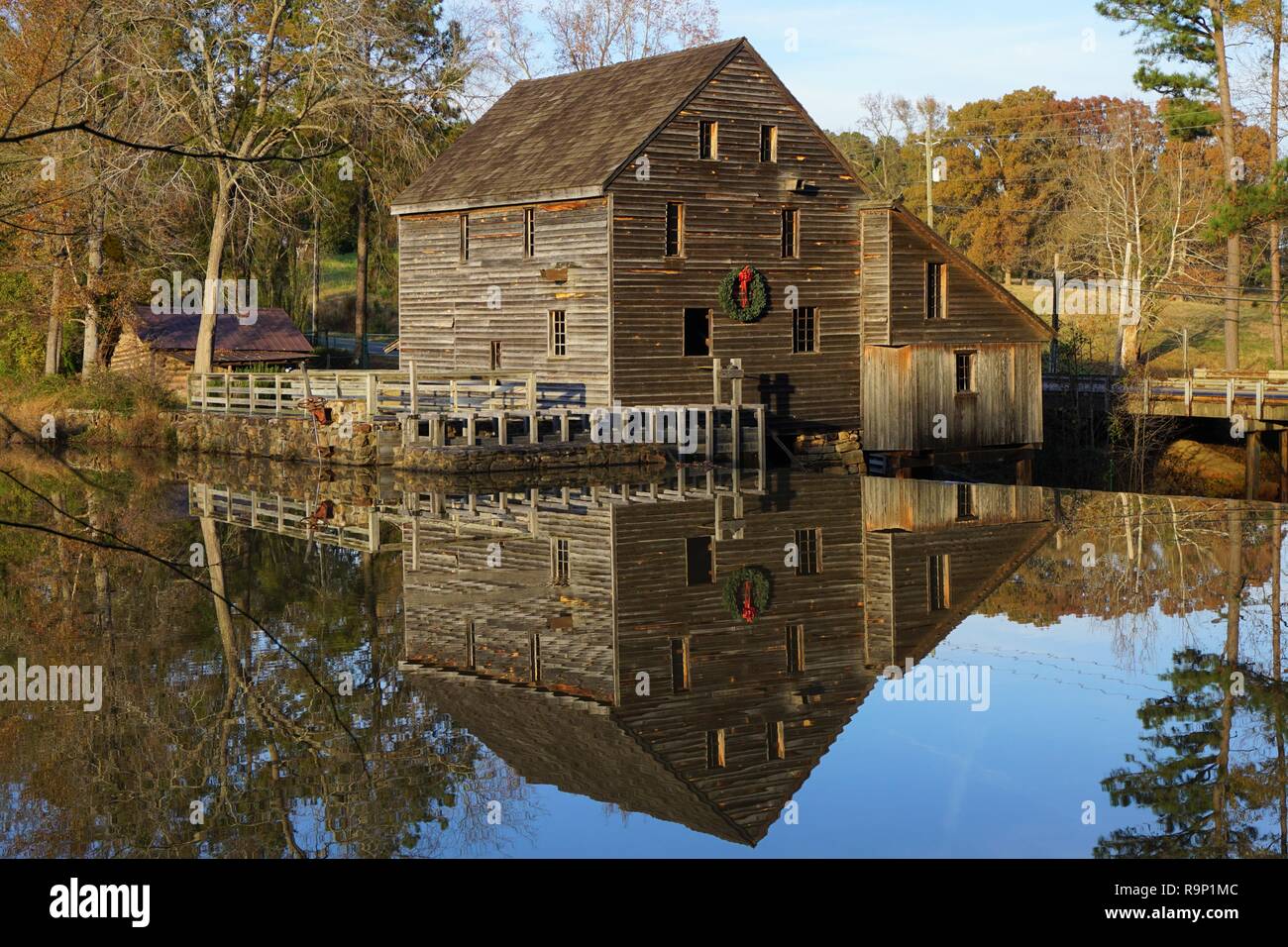 Old mill with holiday wreath reflecting in a pond. Yates Mill in Raleigh, North Carolina Stock Photo