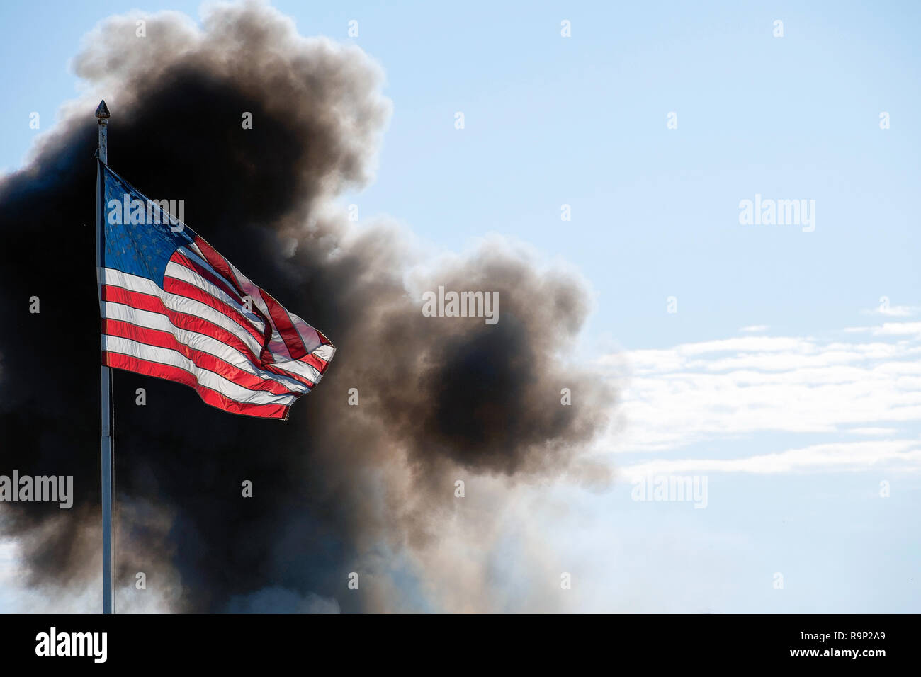 American flag illuminated by sunlight with cloud of black smoke Stock Photo