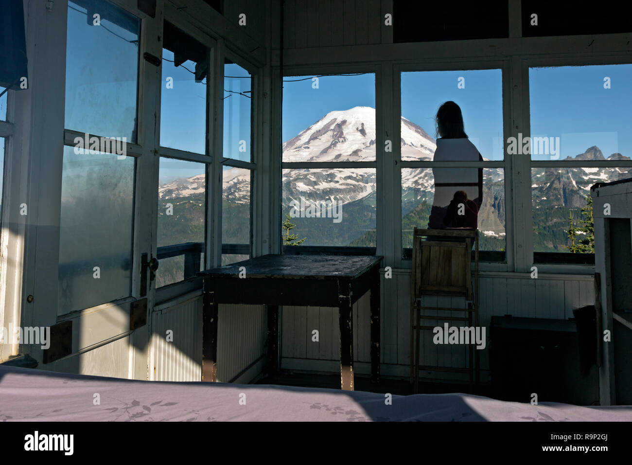 WA15612-00...WASHINGTON - Hiker on the balcony of the Shriner Peak Fire Lookout with Mount Rainier filling the western horizen. Stock Photo