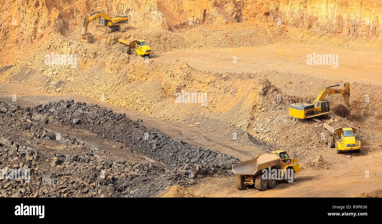 Manganese Mining and Excavator digging and loading ore rocks on a