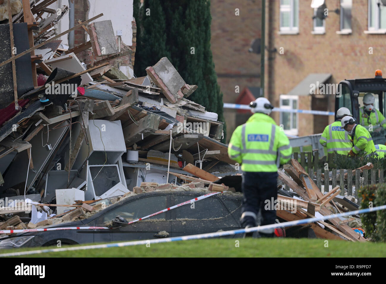 A gas engineer passes a vehicle crushed by debris in Launcelot Close, Andover, where Hampshire Police say that the body of a man has been found after an explosion caused a building to collapse this morning. Stock Photo