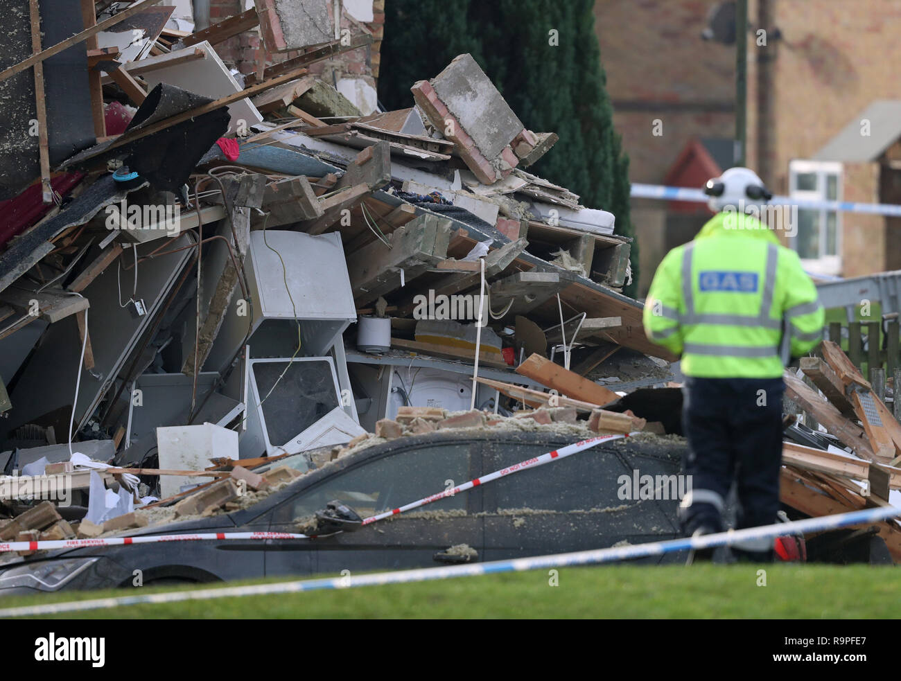A gas engineer passes a vehicle crushed by debris in Launcelot Close, Andover, where Hampshire Police say that the body of a man has been found after an explosion caused a building to collapse this morning. Stock Photo