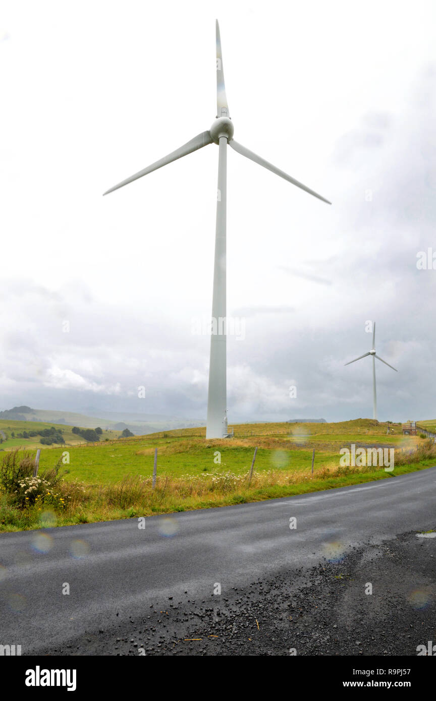 A wind turbine during a storm with wind and rain, in a mountainous region, at the top of a hill. It is a source of ecological electricity, which produ Stock Photo
